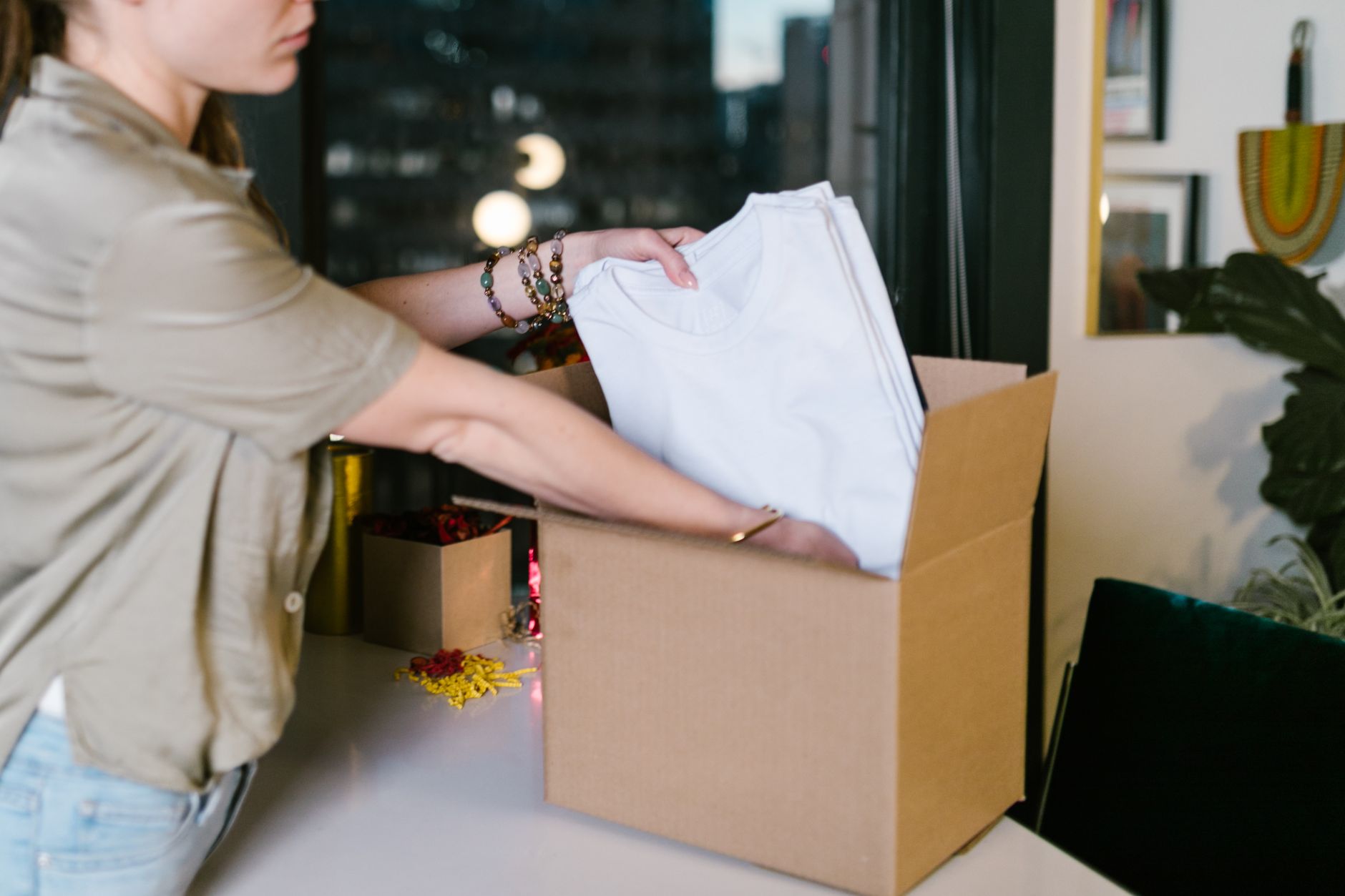 A store owner packing an order at a bench, with a courier label and a scale in front of her.